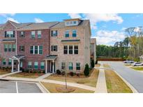 Two-story townhome featuring a brick facade, well-maintained landscaping, and convenient parking spaces at 3420 Reagan Way, Lawrenceville, GA 30044