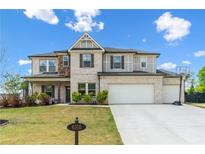 Charming two-story home with a well-manicured lawn, three-car garage, and beautiful mix of brick and siding at 6505 Trailway Trce, Cumming, GA 30041