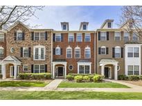 Charming brick townhome featuring black shutters, manicured landscaping, and inviting front entrances at 11265 Musette Cir, Alpharetta, GA 30009