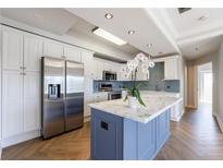 Bright kitchen features stainless steel appliances, white cabinets, subway tile backsplash, and blue kitchen island at 2161 Peachtree Ne Rd # 907, Atlanta, GA 30309