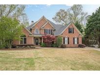 Beautiful two-story brick home featuring a manicured lawn and mature trees at 7405 Richmond Way, Cumming, GA 30040