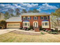 Charming red brick two-story home with blue shutters, bay windows and a well-manicured lawn and landscaping at 4814 Riveredge Cv, Snellville, GA 30039