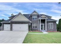 Charming two-story home with a stone facade, well-manicured lawn, and a three car garage at 6793 Oconee Pl, Fairburn, GA 30213