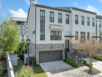 Beautiful three-story home with a gray brick facade, attached garage, and manicured landscaping at 1388 La France Ne St, Atlanta, GA 30307