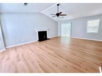 Open living room with vaulted ceilings, fan, fireplace, hardwood floors, and natural light at 440 Sheppard Xing Ct, Stone Mountain, GA 30083