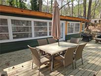 Spacious outdoor deck with dining table and seating, perfect for entertaining surrounded by mature trees at 5440 Portside Dr, Acworth, GA 30101