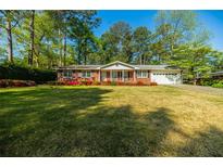 Charming single-story brick home featuring a well-manicured lawn and colorful flower beds at 2972 Ponderosa Cir, Decatur, GA 30033