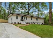 Charming single-story home featuring a black front door, well-kept lawn, and a concrete driveway at 1232 Andrews Dr, Marietta, GA 30062