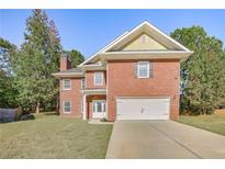 Charming two-story brick home with a well-manicured lawn, a two-car garage, and mature trees at 4066 Wild Orchid Ln, Loganville, GA 30052