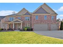 Stately two-story brick home featuring a two-car garage and well-manicured lawn at 4922 Summer Wind Dr, Buford, GA 30519