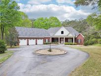 Charming brick home featuring a circular driveway and a spacious three-car garage, surrounded by lush trees at 270 Morrow Rd, Newborn, GA 30056