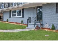 Charming brick home featuring a black wrought iron railing, fresh landscaping, and newly sodded lawn at 3983 E Hilda Cir, Decatur, GA 30035