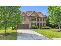 Charming brick two-story home with a well-manicured lawn, mature trees, and a two-car garage at 2369 Apalachee Crucis Ln, Dacula, GA 30019