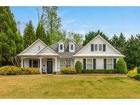 Charming white home featuring a well-manicured lawn and inviting landscaping with mature trees at 133 Newcastle Walk, Woodstock, GA 30188