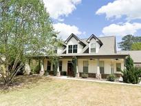 Charming two-story home features a welcoming front porch with decorative columns and a well-manicured lawn at 325 Brook Hollow Ln, Loganville, GA 30052