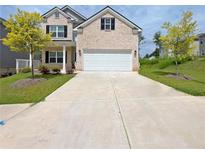 Charming two-story brick home with an attached two-car garage, manicured lawn, and beautiful landscaping at 5119 Aylesbury Ct, Hoschton, GA 30548