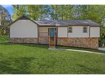 Charming home with a stone foundation, a bright blue front door, and a lush green lawn at 4718 Lou Ivy Rd, Peachtree Corners, GA 30096