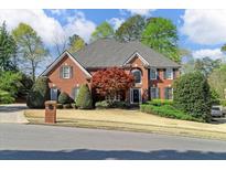 Two-story brick home featuring manicured landscaping, gray roof, black shutters, and a central front door at 3605 Grey Abbey Dr, Alpharetta, GA 30022