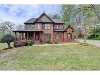 Stately two-story brick home featuring a covered front porch and mature landscaping at 220 Carriage Station Dr, Lawrenceville, GA 30046