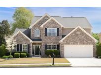 Charming two-story brick home with a well-manicured lawn, attached garage and black shutters at 4215 Evans Farms Dr, Cumming, GA 30040
