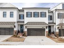 Charming new construction townhomes featuring white brick, metal roof accents, and convenient garage parking at 702 Dodd Ln # 159, Buford, GA 30518