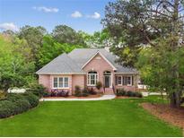 Charming brick home featuring lush lawn, landscaped garden beds, and mature trees in a desirable neighborhood at 2060 Pate Ridge Dr, Loganville, GA 30052