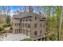 Elegant brick home with multiple garage doors and beautiful architectural details surrounded by lush greenery at 115 Mount Paran Rdg, Atlanta, GA 30327