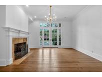 Bright living room with hardwood floors, fireplace, chandelier, and French doors to the backyard at 115 Mount Paran Rdg, Atlanta, GA 30327