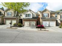 A row of well-maintained townhomes featuring attached garages and landscaped front yards on a tree-lined street at 5556 Cascade Sw Run, Atlanta, GA 30336