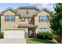 Charming two-story home with a tan exterior, a two-car garage, shuttered windows, and well-maintained landscaping at 5243 Cantbury Way, Atlanta, GA 30349