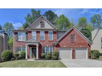 Charming two-story red brick home with a well-maintained lawn, two-car garage and neutral trim at 580 Hammersmith Dr, Suwanee, GA 30024