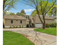 Charming home featuring a driveway, attached garage, and well-manicured front lawn with mature trees at 2470 Woodmere Dr, Marietta, GA 30068
