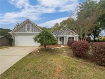 Charming gray home features a two-car garage, well-kept lawn, and lovely landscaping at 2021 Emerald Dr, Loganville, GA 30052
