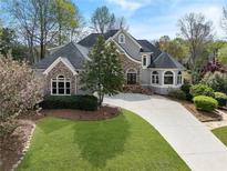 Stunning stone and stucco home with lush lawn, meticulously maintained landscaping, and a curved driveway at 315 Stanyan Pl, Alpharetta, GA 30022