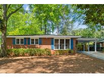 Charming one-story brick home with blue shutters and a cozy carport surrounded by mature trees at 3700 Sexton Woods Dr, Chamblee, GA 30341