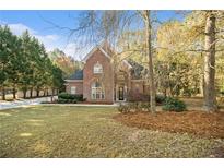 Charming two-story brick home featuring a well-manicured lawn and mature trees at 1418 Brighton Pl, Loganville, GA 30052