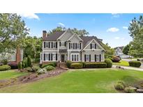 Beautiful two-story home with a well-manicured lawn, mature trees, and a classic front facade at 295 Sagamore Nw Cv, Sugar Hill, GA 30518