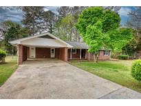 Charming brick home featuring a spacious driveway and a welcoming carport at 1311 Maple Street Se, Conyers, GA 30013