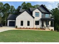 Stunning two-story home features a brick facade, black accents, and a well-manicured lawn at 6132 Hutchins Dr, Buford, GA 30518