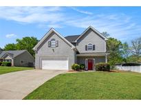 Charming two-story home with gray siding, a well-manicured lawn, and a driveway leading to a two-car garage at 45 Chapman Way, Covington, GA 30016