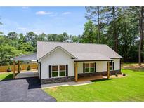 Beautiful one-story home with a white exterior, black shutters and a covered carport at 1765 Harmony Rd, Temple, GA 30179