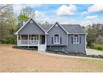 Charming home featuring a stone porch, gray siding, and landscaped front yard at 65 Indian Springs Ne Dr, Rydal, GA 30171