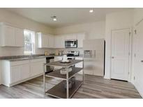 A spacious kitchen features white cabinets, granite countertops, stainless steel appliances, and an island at 7763 Sudbury Cir, Covington, GA 30014