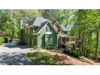 Charming green two-story home with stone accents, inviting front porch, and well-manicured lawn at 104 Kremer Falls Trce, Canton, GA 30114