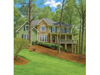 Charming two-story home with a mix of green siding and stone, complemented by a beautifully landscaped front yard at 104 Kremer Falls Trce, Canton, GA 30114