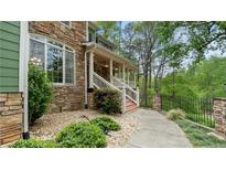 Stone and green siding with a covered porch and well-manicured landscaping welcomes you home at 104 Kremer Falls Trce, Canton, GA 30114