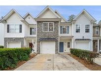 Charming townhome featuring a stone accent, garage, and well-maintained landscaping at 2991 Greyhawk Ln, Cumming, GA 30040