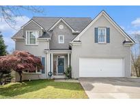 Charming two-story home with gray brick, shutters, landscaped yard, and a two-car garage at 105 Blackberry Ct, Woodstock, GA 30188