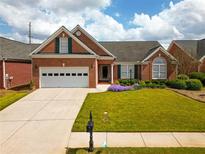Charming brick home featuring an attached two-car garage and a beautifully manicured lawn at 1042 Pecan Grove Pl, Lawrenceville, GA 30046