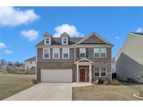 Charming two-story home featuring a brick facade, attached garage, and well-maintained front yard at 5372 Fountain Head Ln, Auburn, GA 30011